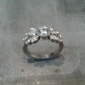 custom designed white gold engagement ring by sean ferguson with round cut diamond and diamond leaf accents