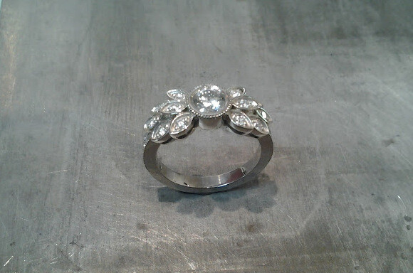 custom designed white gold engagement ring by sean ferguson with round cut diamond and diamond leaf accents