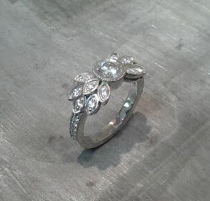 custom designed white gold engagement ring by sean ferguson with round cut diamond and diamond leaf accents side view