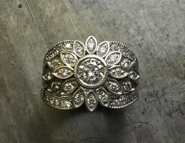 intricate thick custom engraved band with round center diamond and surrounding marquise diamonds in a flower setting