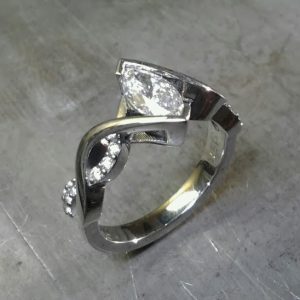 infinity white gold band engagement ring with diamonds and marquise tension set center diamond side view