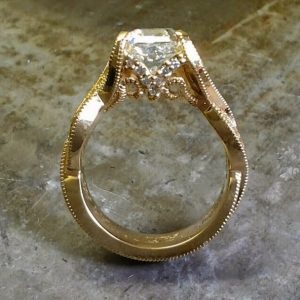 gold intricate engagement ring with princess cut diamond floating in channel setting side view