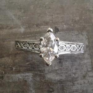 intricate filigree white gold band with delicate marquise cut diamond in cathedral setting engagement ring top view