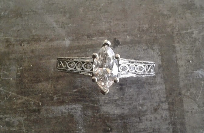 intricate filigree white gold band with delicate marquise cut diamond in cathedral setting engagement ring top view