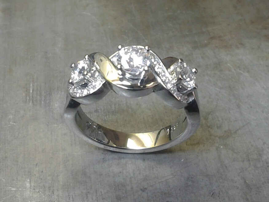 custom designed white gold engagement ring with swirled band and triple set diamonds