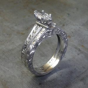 intricate filigree band with marquise center stone in a cathedral setting side view