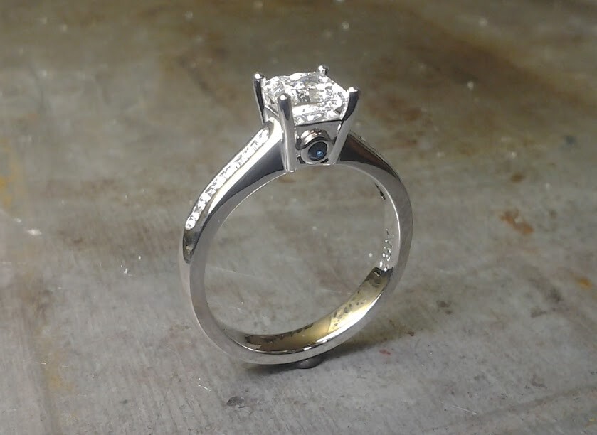Princess cut engagement ring with sapphire in side and diamonds down shank