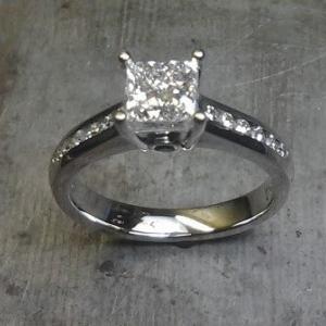 Princess cut engagement ring with sapphire in side and diamonds down shank