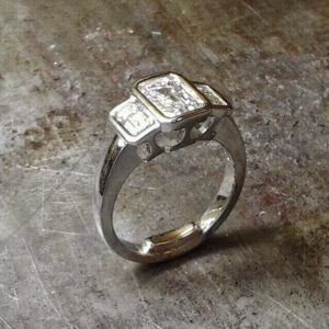 3 stone emerald cut bezel engagement ring