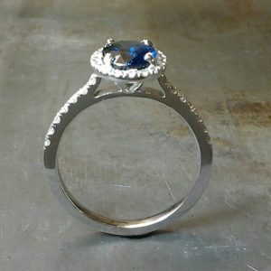 Finger through view Royal Blue Sapphire set in 19k white gold with diamond set halo and sides